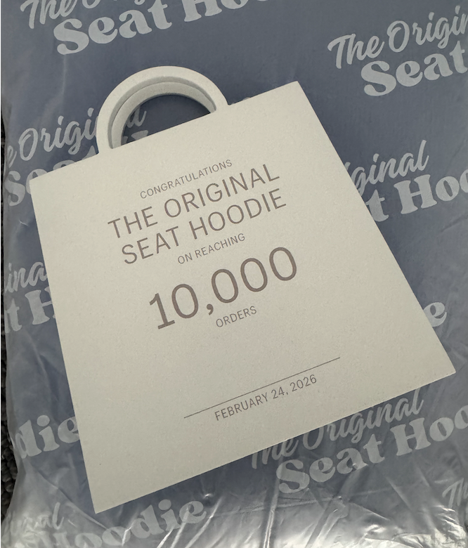 White Shopify Milestones bag award personalized for The Original Seat Hoodie, inscribed 'Congratulations The Original Seat Hoodie on reaching 10,000 orders. February 24 2026'